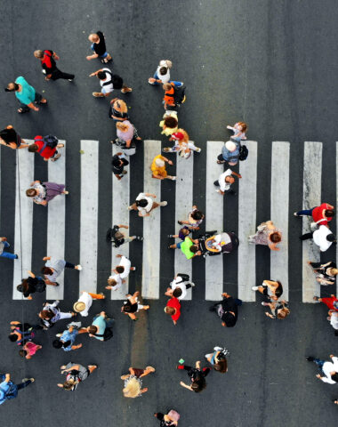 Aerial. People crowd motion through the pedestrian crosswalk. Top view from drone.