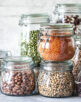 Set of different legumes in glass jars on, concrete white table. A source of protein for vegetarians. The concept of healthy eating and food storage.