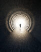 Concept or conceptual dark tunnel with a bright light at the end or exit as metaphor to success, faith, future or hope, a black silhouette of walking man to new opportunity or freedom 3d illustration