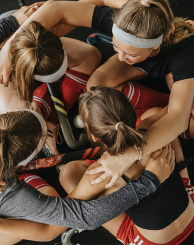 Hockey players huddling while crouching on floor in health club