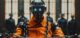 ai robot sentenced in court in orange jumpsuit, chained and seated in a prison setting. The background includes guards, highlighting themes of artificial intelligence, control, and dystopian scenarios