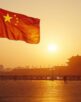 Chinese flag waving at sunset near iconic landmark