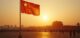 Chinese flag waving at sunset near iconic landmark