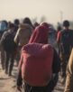 Group of refugees standing in a barren landscape, wearing backpacks. Harsh lighting casts long shadows, symbolizing displacement and crisis. A diverse and resilient community, united in their journey